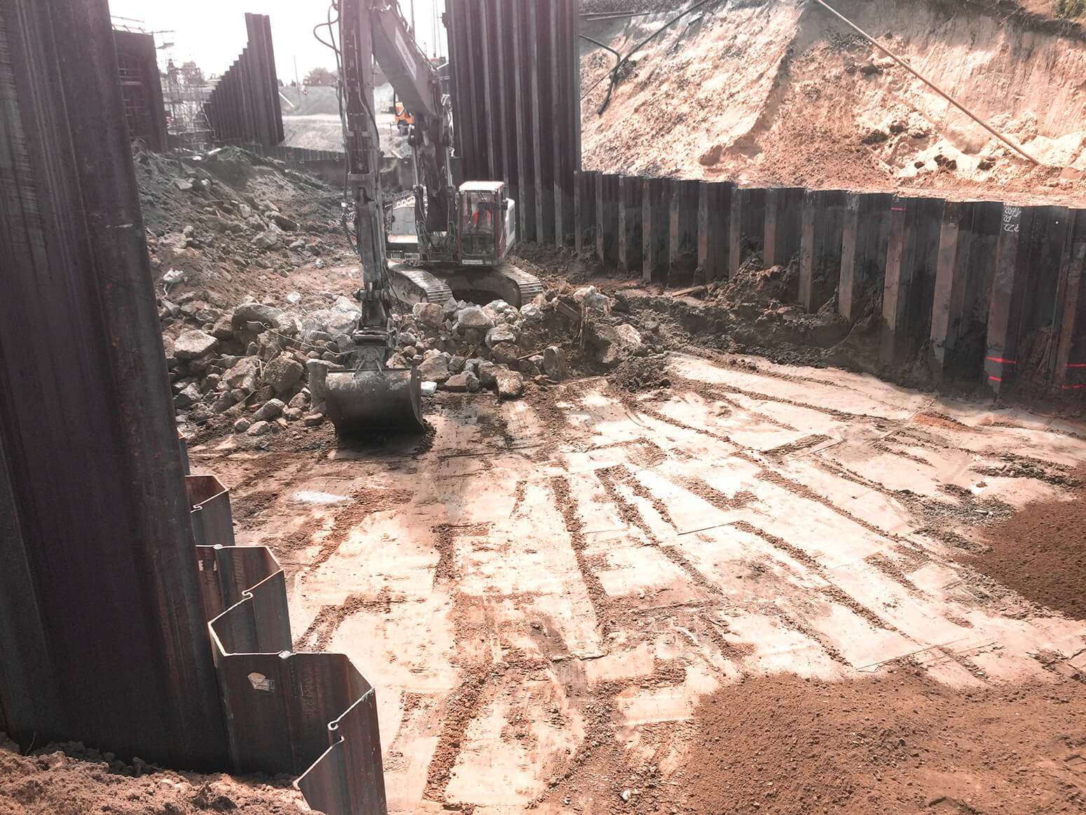 An excavator between sheet-pile walls removing an old railway embankment and bridges