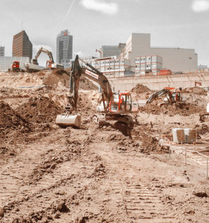 Excavation pit of the Mall of Berlin with several excavators and trucks, in the background the DB building at Postdamer Platz.