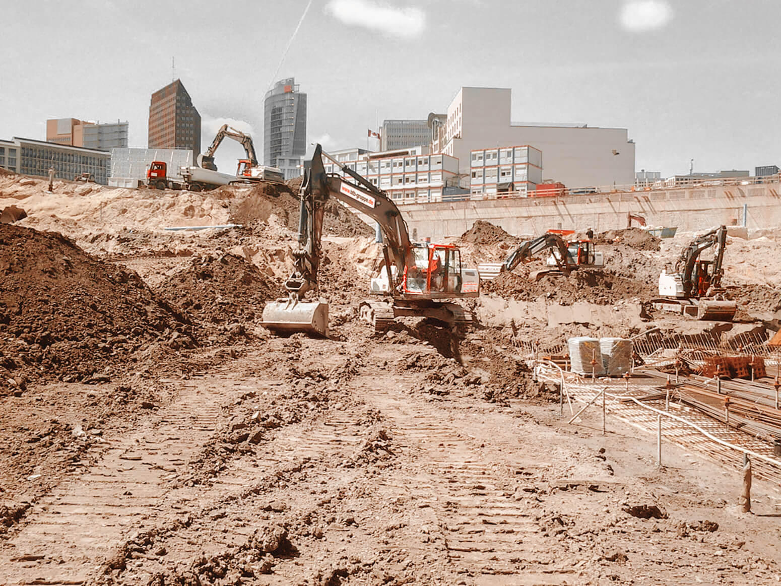 Excavation pit of the Mall of Berlin with several excavators and trucks, in the background the DB building at Postdamer Platz.