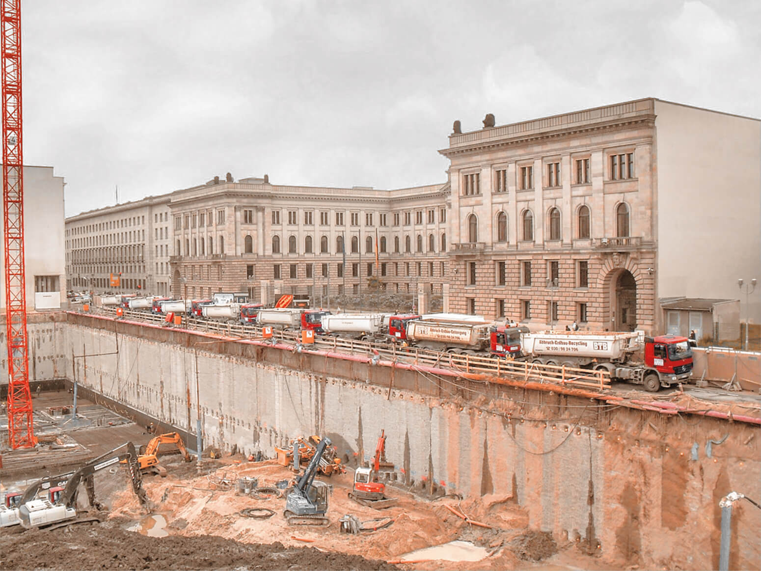 Baugrube für die Mall of Berlin mit mehreren Baggern und einem Kran, mehre LKW warten zur Abfuhr des Erdaushubs am Rand