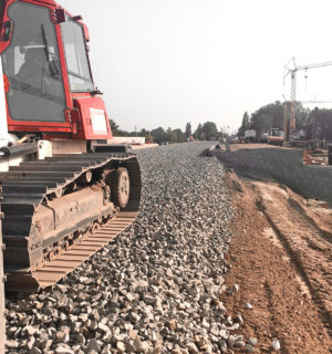 eine Walze von BTB bringt Bahnschotter für einen neuen Bahndamm auf