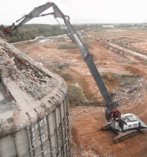 Luftaufnahme des Abrisses eines hohen Gebäudes durch eine schwere Baumaschine