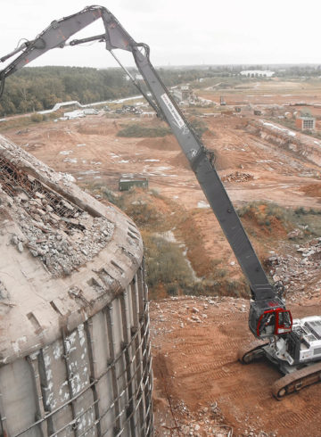 Luftaufnahme des Abrisses eines hohen Gebäudes durch eine schwere Baumaschine