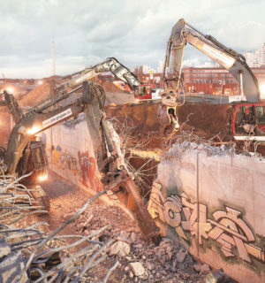 mehrere schwere Baumaschinen brechen am späten Abend einen Tunnel aus Stahlbeton ab