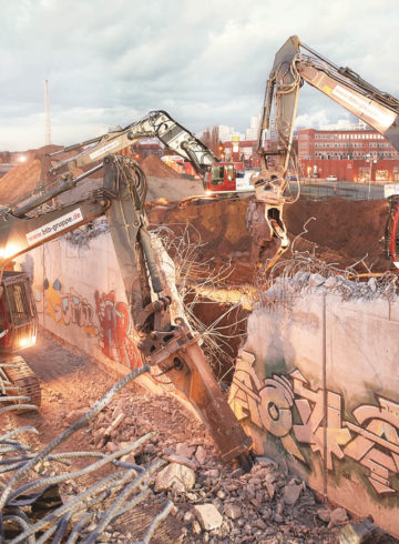 Several heavy construction machines demolish a reinforced concrete tunnel late in the evening