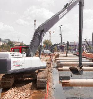 Bagger heben unter Wasser Boden aus, im Hintergrund der Berliner Hauptbahnhof