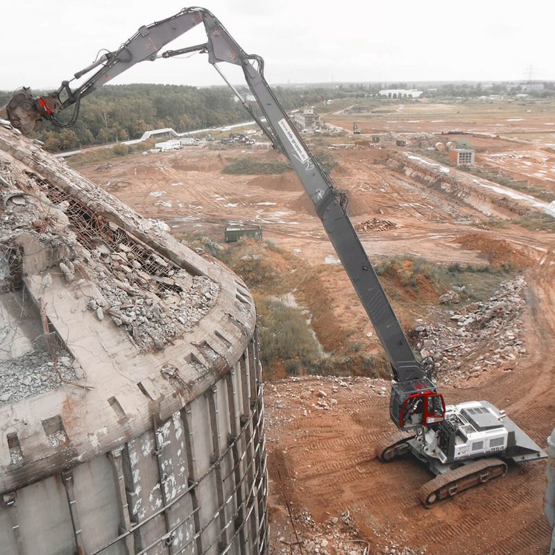 Luftaufnahme des Abrisses eines hohen Gebäudes durch eine schwere Baumaschine